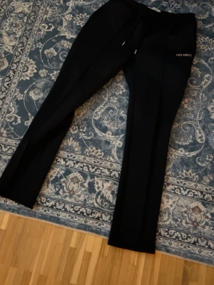Svarta kostymbyxor från Les Deux - Säljer ett par svarta kostymbyxor från Les Deux med rak passform och pressveck. Byxorna har dragsko i midjan och diskret logga broderad vid fickan. Perfekta för en clean och stilren look.