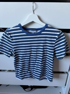 Randig blåvit t-shirt från Topshop - Säljer en kortärmad topp från Topshop med blå och vita ränder. T-shirten har rund halsringning med blå kant