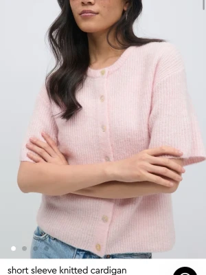 rosa kofta  - PRIS KAN DISKUTERAS! Aldrig använt Supersöt ljusrosa kofta från Gina Tricot i ullblandning. Koftan har korta ärmar, rund halsringning och knäpps med stora pärlemorknappar framtill. Perfekt att styla över ett linne eller t-shirt för en trendig lager-på-lager-look.