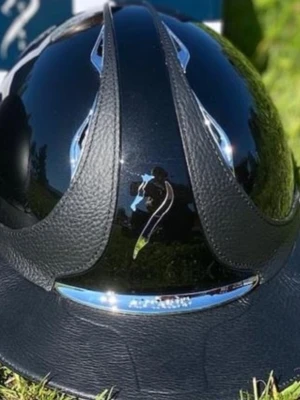 Svart ridhjälm från Samshield - Snygg svart ridhjälm från Samshield med blank finish och detaljer i konstläder. Hjälmen har en elegant form med kromade inslag och klassisk skärm. Perfekt för dig som vill ha en stilren och modern look i stallet.