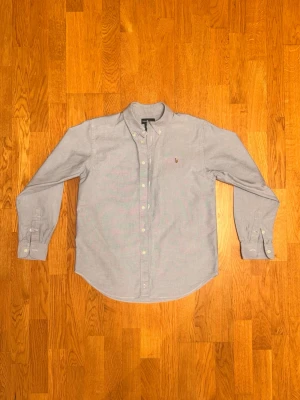 Ljusblå Polo Ralph Lauren skjorta - Säljer en ljusblå skjorta från Polo Ralph Lauren. Skjortan är i storlek 16 som motsvarar S i herrstorlek. Skjortan har en liten defekt på magen som syns på en bild. Var inte rädd för några frågor!