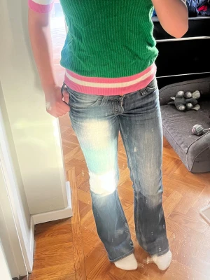 Grön ribbad tröja med rosa detaljer - Säljer en grön ribbad trö från from future med korta ärmar och rosa ränder vid hals, ärmslut och nederkant. Tröjan har en figurnära passform och är tillverkad i ett stickat material som känns mjukt och bekvämt. Perfekt för dig som gillar färg och vill ha en unik look. 