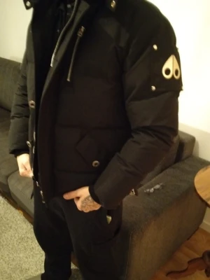 Rätt ny  jacka knucke passar medlem  - Säljer en svart pufferjacka från  med stor huva och snygga detaljer i silver. Jackan har dragkedja, knappar och fickor med lock. Klassisk patch på ärmen och fluffig krage. Perfekt för kalla dagar och riktigt stilren look. Mindre i storlek 