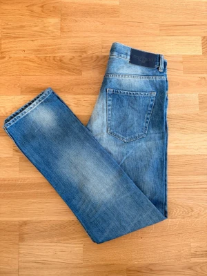 Sällsynta Jimmy Choo x H&M Limited Edition Jeans för herr – Storlek 31 (M) - Uppgradera din denim-samling med dessa ikoniska jeans från det eftertraktade samarbetet Jimmy Choo for H&M. Ett riktigt samlarobjekt för den modeintresserade! • Märke: Jimmy Choo x H&M • Passform: Classic Straight Leg (Raka ben) • Storlek: W31 (Motsvarar Medium) • Material: 100% Premium-bomull • Skick: Mycket gott vintageskick. Snygg autentisk tvätt med naturlig slitning. • Detaljer: Försedda med den karaktäristiska "Jimmy Choo for H&M"-läderpatchen baktill och märkesetiketter på insidan. 