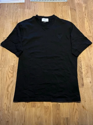 Svart t-shirt från Ami Paris - Helt ny säljer för den ej passa. Säljer en svart t-shirt från Ami Paris med det ikoniska hjärta-A broderiet på bröstet. T-shirten har rund hals, korta ärmar och är gjord i mjuk bomull. Enkel men stilren design som passar till det mesta. Priset beror på att jag vill bli av med den då den bara ligger.