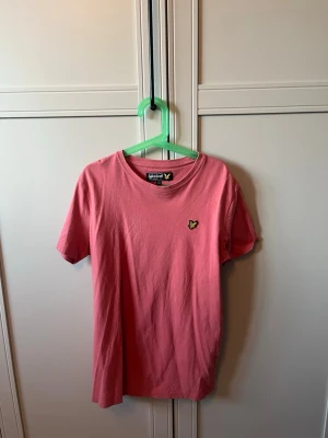 Orange t-shirt från Lyle & Scott - Snygg orange t-shirt från Lyle & Scott med klassisk gul logga på bröstet. T-shirten har rund halsringning och korta ärmar. Tillverkad i mjuk bomull som är skön att bära hela dagen.