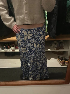 Blåvit långkjol från Lindex XS - Säljer en blåvit långkjol från Lindex i storlek XS. Kjolen har ett blommigt mönster och är tillverkad i ett lätt och luftigt material, perfekt för varma dagar. Köptes förra året och har använt typ 3 gånger så den är i nyskick 