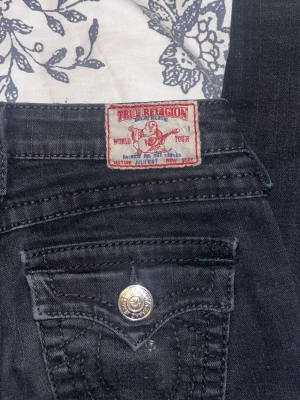 Svarta skinny jeans från True Religion - Snygga svarta skinny jeans från True Religion , Tillverkade i stretchigt denim för skön passform. Storlek 25 (typ xs/s). lätta att sy om till bootcut (jag har gjort med ett par nästan exakt likadana) säljer då dom är för små💕