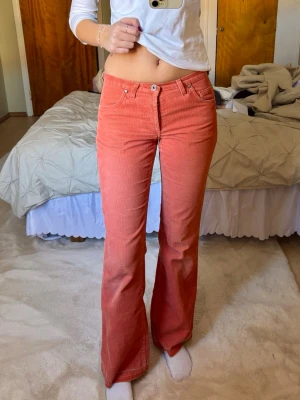 Lowwaist utsvängda jeans korall - Suuupersnygga och unika manchesterbyxor/jeans som är korallfärgade😍 de är i använt skick men lika snygga ändå! Lite slitet runt knapparna men fyller fortfarande sin funktion. Midjemåttet tvärs över är 36cm och innerbenslängden är 80cm💕 Jag är 172 för referens