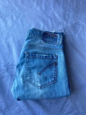 Dondup George jeans-Ljusblå slim/baggy-W33 - Säljer ett par ljusblå skinny jeans med råa benslut och slitna detaljer framtill. Jeansen har klassisk femficksmodell och är tillverkade i denim med stretch för skön passform. Perfekta till sneakers eller boots. Korta i längden runt L29/30 och waist är 33