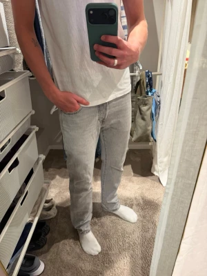 Ljusgrå raka Levi’s jeans - Säljer ett par ljusgrå Levi’s jeans med rak passform och klassisk femficksdesign. Jeansen är i bra skick, har förstärkt dem i skrevet då de hade slitits lite. Jag är 188 lång och de passar mig bra!