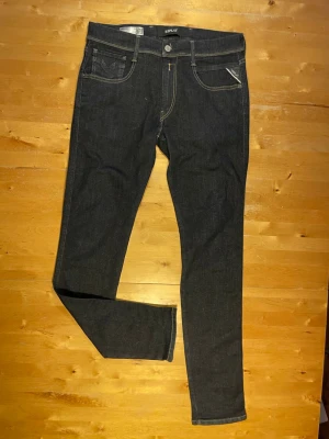 Mörkblå skinny jeans från Replay - Snygga mörkblå skinny jeans från Replay med klassiska fem fickor och kontrastsömmar. Jeansen har en smal passform och är tillverkade i stretchigt denimtyg för extra komfort. Perfekta för en trendig och avslappnad look.