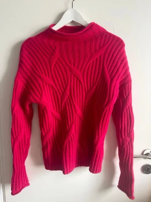 Knallrosa hotpink  stickad tröja från Hobbs - Snygg hotpink stickad tröja från Hobbs med coolt ribbat mönster och hög hals. Tröjan har långa ärmar och är gjord i ett tjockare material som känns både trendigt och bekvämt. Perfekt för dig som vill ha något färgstarkt och unikt i garderoben.