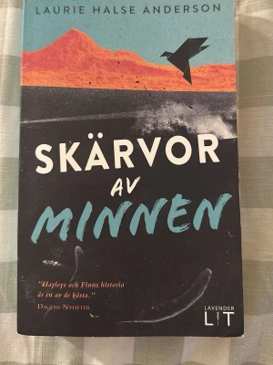 Skärvor av minnen pocketbok - En pocketbok med titeln 'Skärvor av minnen' av Laurie Halse Anderson. Omslaget har en mix av svart, turkos och orange med en grafisk fågel och berg. Boken är tryckt på papper och ges ut av Lavender Lit.