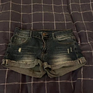 Svarta jeansshorts med fransar - Snygga svarta jeansshorts med slitningar och fransig kant. Shortsen har fem fickor, knapp och dragkedja framtill samt en tvättad look som ger en cool vibe. Perfekta för sommardagar och festivaler.
