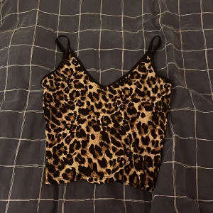 Leopardmönstrad croppad linnetopp - Snygg croppad linnetopp med leopardmönster och tunna svarta axelband. Perfekt för dig som vill sticka ut och addera lite edge till din outfit. Mjuk och stretchig känsla, passar till både jeans och kjol.