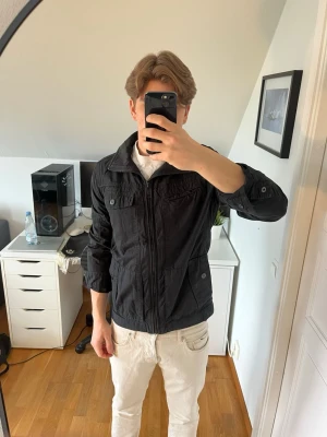 Svart fieldjacka med fickor och dragkedja  - Säljer en svart fieldjacka från Esprit med dragkedja framtill och fyra fickor med lock och knapp. Jackan har en klassisk krage och är långärmad. Hör gärna av dig vid frågor!