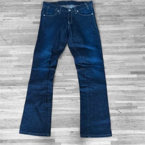 G-star jeans - Säljer ett par mörkblå bootcut jeans från g-star med klassisk femficksdesign och kontrastsömmar. Jeansen har vida ben och är tillverkade i kraftigt denimtyg. Perfekta för dig som gillar retrovibbar och vill ha en avslappnad men snygg look.