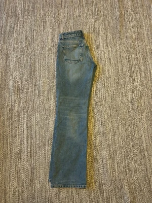 Blå raka jeans med medelhög midja - Säljer ett par klassiska blå jeans med rak passform och medelhög midja (mid rise). Jeansen har fem fickor och stängs med dragkedja och knapp. Perfekta till en avslappnad stil och passar till det mesta. 