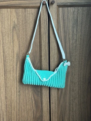Ribbad Mint Axelväska Bomull  - En ribbad axelväska. På ringarna står det believe. Materialet är en blandning av akryl och bomull.