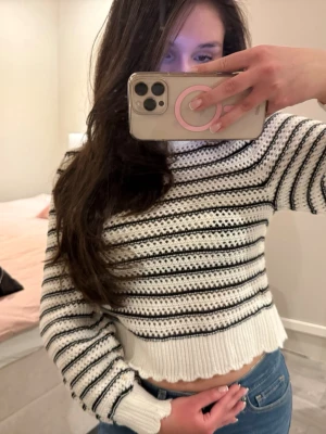 Vit stickad tröja med svarta ränder - Trendig vit stickad tröja med svarta horisontella ränder och croppad passform. Tröjan har långa ärmar, ribbade muddar och öppen rygg. Tröjan har endast använt en gång och i storlek xs🌸