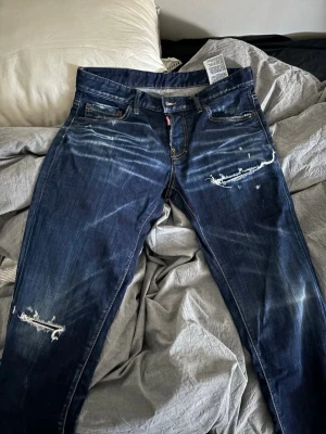 Mörkblå slitna jeans från Dsquared2 - Säljer ett par mörkblå jeans från Dsquared2 i storlek 46. Jeansen har slitningar och distressed detaljer på benen. Säljer dem för att de inte passar längre. Kvitto från farfetch finns.