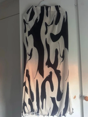Plisserad svartvit långkjol - Säljer en  långkjol med svartvitt zebramönster. Kjolen har elastisk midja och är gjord i ett lätt, flödande material 