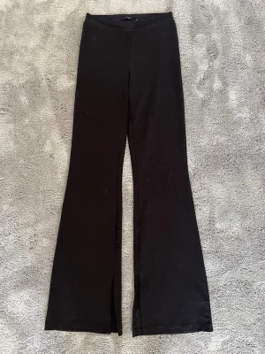 Svarta utsvängda leggings från lager 157 - Säljer ett par svarta leggings från lager 157 med utsvängda ben och hög midja. De är tillverkade i ett stretchigt material som sitter skönt och följer kroppen. Perfekta för dig som gillar en enkel men trendig look.