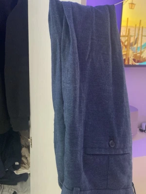 Mörkblå kostymbyxa i linne slim fit - Snygga mörkblå kostymbyxor i linne med slim fit passform. Byxorna har raka ben, knappdetalj vid bakfickan och stilren design som passar perfekt till en dressad look. Materialet är luftigt och ger en modern känsla.