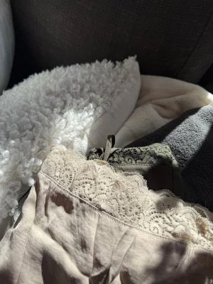 Linnen med spetsdetaljer - Säljer två  linnen med tunna axelband och vacker spets längs urringning och nederkant. Materialet känns mjukt och svalt, perfekt för mysiga kvällar hemma. Spetsen ger en romantisk touch och nattlinnet har en avslappnad passform. Priset är för bägge. Använda max 1 gång.