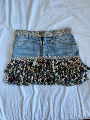 Blommig jeanskjol med volang - Unik kort jeanskjol med volang.