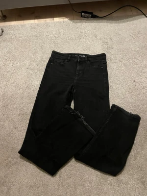 Svarta jeans från Denim - Säljer ett par svarta bootcut/raka jeans från Denim i storlek 36. Klassisk femficksmodell med smal passform och normal midja. Jeansen är tillverkade i stretchigt bomullsmaterial för extra komfort och sitter snyggt längs benen.