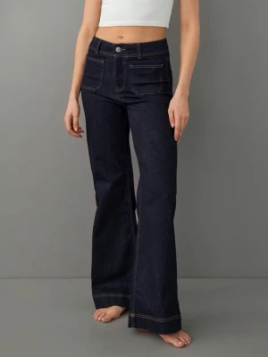 Mörkblå bootcut jeans  - Säljer ett par mörkblå bootcut jeans med vita kontrastsömmar och höga fickor fram. Jeansen har hög midja, raka ben och klassisk knappgylf. Perfekta för dig som gillar retrovibbar och vill ha ett par jeans som sticker ut lite extra. Fickor i fram som gör jeansen unika. Långa!! Helt oanvända!! Stretchiga. 