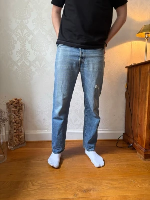 Blå raka jeans från Acne Studios - Säljer ett par klassiska blå jeans från Acne Studios med rak passform och normal midja. Jeansen har en snygg tvättad look och subtila slitningar på låret. Tillverkade i denim med Acne Studios läderpatch bak i midjan. Storleken är 29/32 och skicket är 8/10! Nypris cirka 4500kr