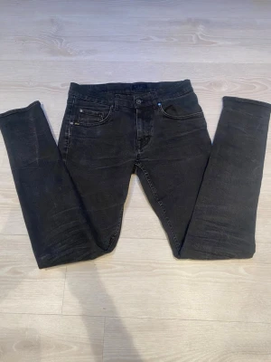 Svarta slim jeans från tiger of sweden - Säljer ett par svarta slim jeans från Tiger of sweden med klassisk femficksmodell och diskret logga på bakfickan. Jeansen har en tight passform och är gjorda i stretchigt denimtyg för extra komfort. Perfekta för en clean och stilren look.