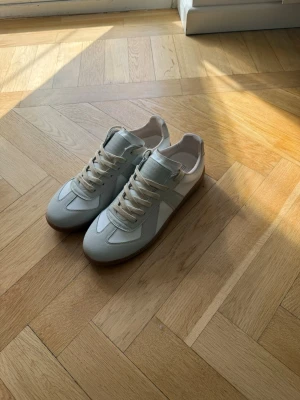 Maison Margiela sneakers - Hej! Säljer ett par Maison Margiela sneakers i storlek 42. Skorna är i nyskick och är vit- och gråfärgad. Till skorna medföljer originallåda.