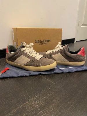 Zadig & Voltaire grå sneakers - Snygga sneakers från Zadig & Voltaire i grå mocka med beige detaljer och vit sula.  Oanvända sulor! 