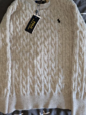 Grå kabelstickad tröja Polo Ralph Lauren - Kabelstickad grå tröja från Polo Ralph Lauren, OBS PASSAR XS INTE S. Kan diskutera pris med snabb affär