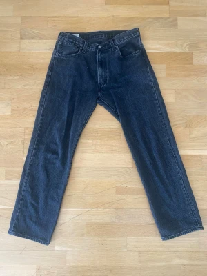 Levi's 555 svarta raka jeans - Säljer ett par klassiska svarta raka jeans från Levis som blivit för små. Bra skick men väl använda. Midja:45 CM, Stussvid: 55 CM & Innerben: 75 CM.