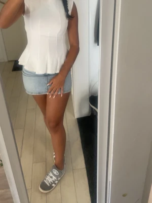 Vit ärmlös peplumtop - Säljer en söt vit topp med peplumvolang och ärmlös design. Toppen har en figurnära passform upptill och släpper ut nedtill för en feminin siluett. Perfekt att matcha med kjol eller jeans för en fräsch look. Använd en gång.