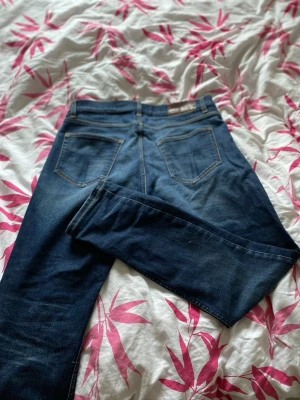 Mörkblå raka jeans med kontrastsömmar - Säljer ett par mörkblå jeans från tiger of Sweden med raka ben och klassiska kontrastsömmar. Jeansen har två bakfickor och en läderpatch i midjan. Materialet är denim i bomull och passformen är tidlös och enkel.