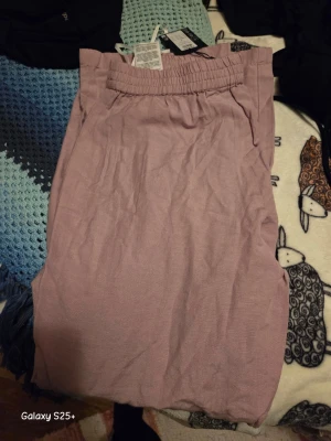 Ljuslila byxa med resårmidja - En enkel och stilren ljuslila byxamed bekväm resår i midjan. Kjolen har en rak passform och är tillverkad i ett mjukt tyg som passar perfekt för vår och sommar. Snygg att matcha med både t-shirt och blus.