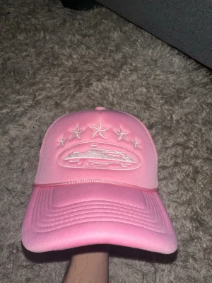 Rosa corteiz keps - Säljer en oanvänd rosa corteiz keps. Kepsen har böjd skärm och justerbar baksida. Perfekt för dig som vill sticka ut med en färgglad accessoar.
