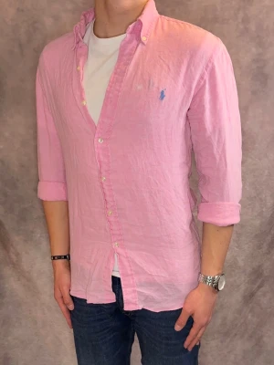 Rosa Ralph Lauren Linneskjorta - Stl S, Slim fit - Riktig snygg Ralph Lauren Linneskjorta i rosa med  ljusblå pony, perfekt till sommaren som närmar sig! 🏖️🌊 | Fint skick: 8,2/10, finns en vit fläck på bröstet, därav priset | Stl: S |  Modellen är 177cm och väger 75kg, sitter grymt  | Hör av dig vid frågor // Galgen 🫡 