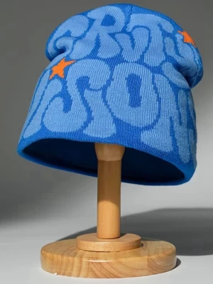 Blå mönstrad mössa med stjärnor - Cool blå mössa med ljusblå textmönster och orange stjärnor. Mössan har en avslappnad passform och är stickad i mjukt material, perfekt för att ge din outfit en färgklick. Snygg och trendig accessoar för kalla dagar.