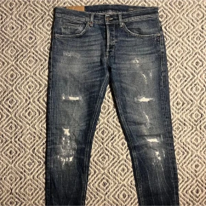 Dondup George  - Snygga blå skinny jeans med slitningar och distressed detaljer framtill. Jeansen har klassiska fem fickor och dragkedjor på bakfickorna för en extra cool look. Perfekta för dig som gillar en trendig och avslappnad stil. Storlek 33 43cm 103cm🌟