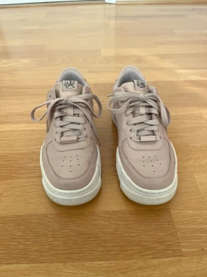 Nike Air Force 1 Shadow – storlek 38 - Säljer ett par Nike sneakers i storlek 38 i en stilren beige färg med vit sula. Skorna är i gott använt skick med normalt slitage för användning, men fortfarande mycket fina och välbevarade som ni ser på bilderna. Bekväm modell som passar både till vardag och mer uppklädda outfits.