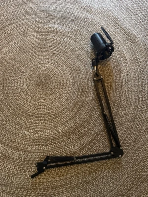 Svart mikrofon med stativ och popfilter - Säljer en svart mikrofon med tillhörande justerbart stativ och popfilter. Perfekt för streaming, podd eller gaming. Mikrofonen är cylinderformad och stativet är i metall med fjädrar för stabilitet. Enkel att montera på skrivbord.