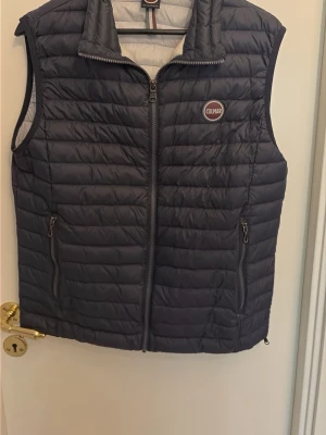 Mörkblå dunväst från Colmar - Snygg mörkblå dunväst från Colmar med quiltad design och dragkedja framtill. Västen har två praktiska fickor med dragkedja och en hög krage. Perfekt för lager-på-lager och har en sportig look med Colmar-logga på bröstet.