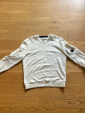 Vit sweatshirt från C.P. Company - Vit sweatshirt från C.P. Company. Tröjan är L men sitter mer som en M. 